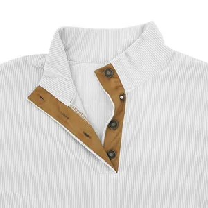 Gros plan sur le col d'un sweat en velours côtelé blanc et patte marron boutonnée