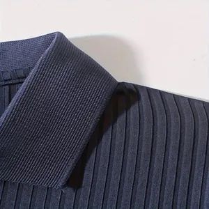 Detailopname van de kraag van een marineblauwe geribbelde polo met stoftextuur.
