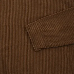 High-quality close-up of brown corduroy fabric texture showing sleeve cuff detail and stitching