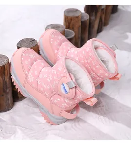 Dettaglio di stivali da neve rosa per bambini con motivo a fiocchi di neve e calda fodera in pelliccia.