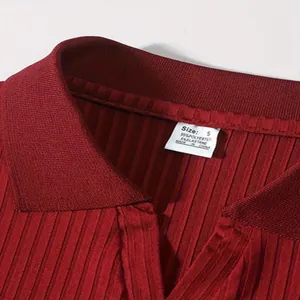 Detailopname van een geribbelde rode poloshirtkraag met maat S en het materiaaletiket
