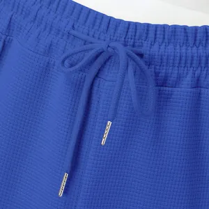 Detailed macro view of blue waffle knit pants waistband featuring an adjustable drawstring