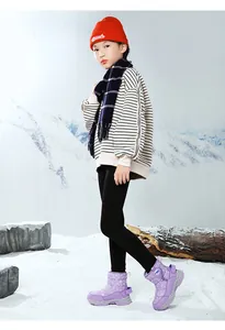 Vista dettagliata di bambina con stivali da neve viola con motivo a fiocchi di neve