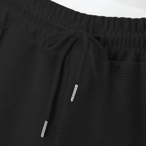 Macro detail of black waffle knit waistband with adjustable drawstring and metal tips