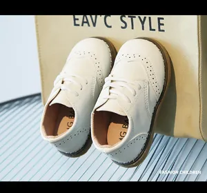 Macro view of white children's leather brogue shoes showing soft texture and stitching