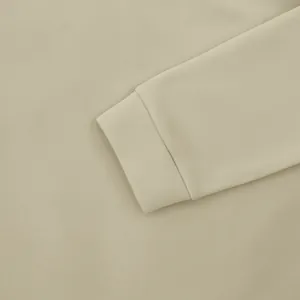 Detailopname van het geribbelde manchet van een kaki herenshirt met lange mouwen.