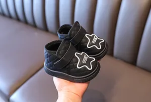 Close-up detail of black quilted baby snow boots with star patch and adjustable strap