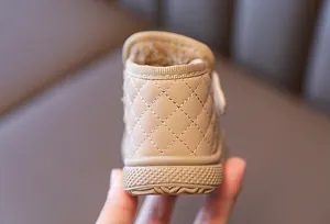 Detailed macro view of beige toddler snow boot with diamond stitching and plush lining