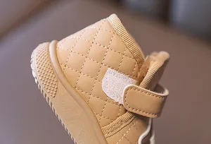 Close-up of beige quilted baby snow boot showing velcro strap and fleece lining.