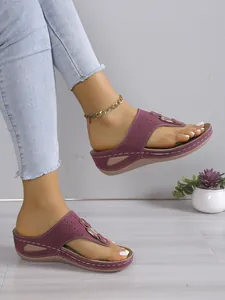 Detaillierte Seitenansicht eleganter weinroter Keilsandalen, getragen von einem Model