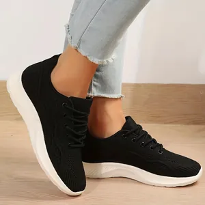 Détail de baskets en maille noire respirante avec semelles souples blanches sur bois