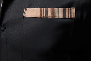 Détail de la poche d'une chemise noire pour homme avec garniture rayée rétro