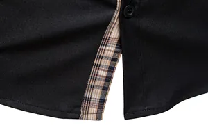 Détail de l'ourlet d'une chemise noire pour homme avec fente à carreaux beige.