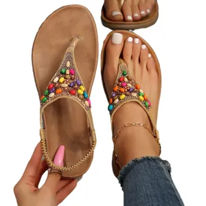Sandali infradito piatti bohémien da donna con perline colorate su plantare marrone.