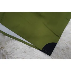 Gros plan d'un tissu vert à pois avec un ourlet soigné sur un tapis en fourrure blanche.