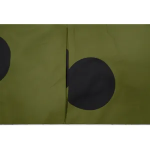 Vue rapprochée montrant le détail de la poche sur une robe olive à gros pois noirs.