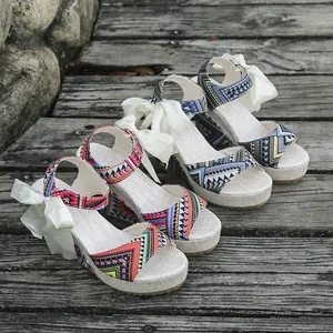 Detailed view of ethnic patterned wedge sandals with elegant white ribbon bows