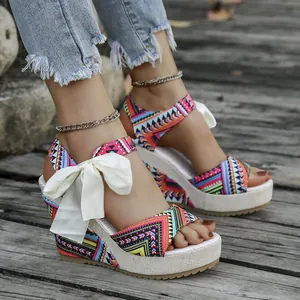 Detailed view of ethnic print wedge sandals featuring a white bow tie and platform heel