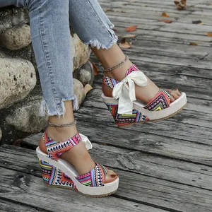 Detailed side view of ethnic print wedge sandals with elegant white ribbon bow tie