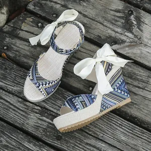 Detailed view of bohemian wedge sandals with ethnic prints and white ribbon bows.
