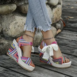 Detail view of ethnic style wedge sandals with colorful pattern and white bow ribbon
