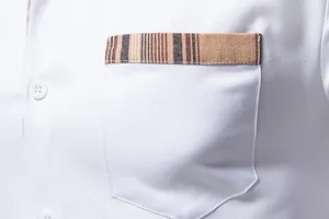 Gros plan de la poche d'une chemise blanche avec une bordure décorative à rayures.