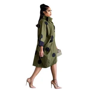 Détail d'une robe chemise olive à pois avec coupe ample et poches latérales.