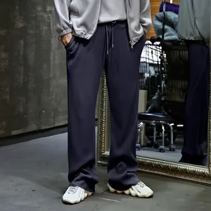 Detalle de pantalones plisados de hombre azul marino con textura acanalada y cordón