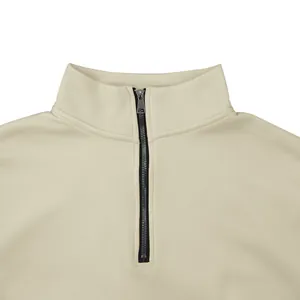 Detailweergave van de zwarte halve rits en opstaande kraag op een beige casual top