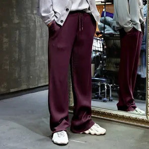 Vista detallada de pantalones plisados burdeos para hombre con pernera ancha y rayas.