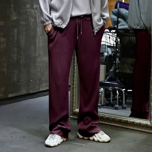 Vista detallada del pantalón plisado burdeos para hombre con corte recto, holgado y alto.