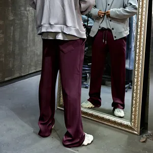 Detalle de los pantalones de hombre granates de pernera ancha con textura de canalé en espejo.