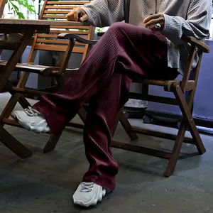 Detalle de pantalones anchos plisados granates para hombre en un ambiente casual