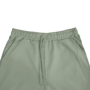 Detail van de elastische tailleband en het trekkoord van de groene casual broek