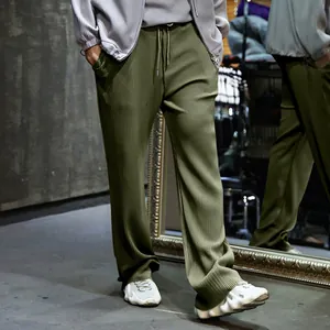 Detalle de pantalones plisados para hombre verde oliva, pierna ancha y cordón ajustable.