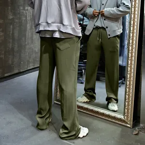 Detalle de pantalón para hombre verde oliva con pernera ancha, textura acanalada y cordón.