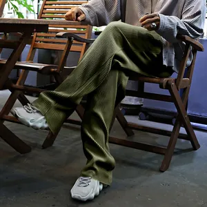 Vista detallada de pantalones anchos plisados para hombre en verde oliva con textura vertical
