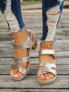 Primer plano de sandalias plateadas con correas cruzadas texturizzate y cierre de velcro
