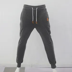 Détail du pantalon de jogging gris foncé pour hommes avec cordon et écusson en cuir