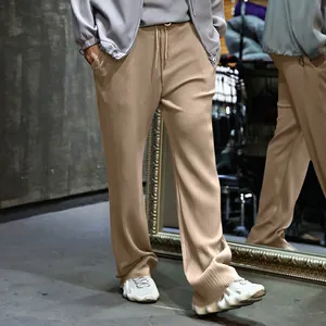 Detalle de pantalones beige de pana para hombre con cordón y corte de pierna ancha.