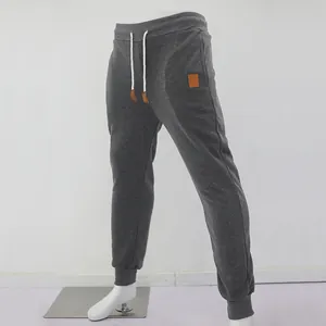 Vue détaillée du jogging pour hommes en polaire gris foncé avec cordon de serrage blanc et écusson