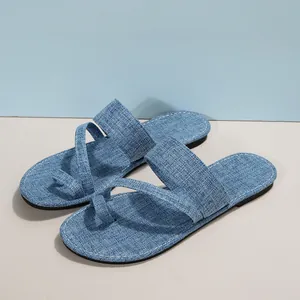 Nahaufnahme blauer Denim-Zehring-Sandalen mit strukturiertem Stoff und flacher Sohle