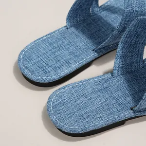 Detailansicht der blauen Denim-Stofftextur bei flachen Damen-Sandaletten und Pantoletten