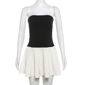 Detail of sleeveless black and white contrast mini dress featuring a pleated skirt.