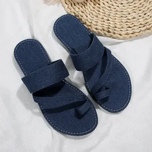 Nahaufnahme von modischen blauen Denim-Zehensteg-Sandalen für Damen auf weißem Stoff