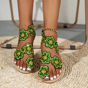 Detailed view of summer sandals featuring vibrant green embroidered flowers with sequins