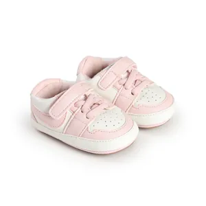 Detailed view of pink and white infant walking shoes with velcro straps and soft soles.