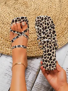 Detailed view of women's leopard print square toe flat sandals on foot and hand-held