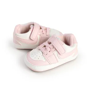 Detail view of stylish pink and white baby walking shoes with adjustable hook and loop