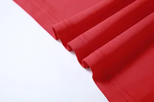 Close-up of vibrant red dress fabric showing fine texture and double-stitch hem.